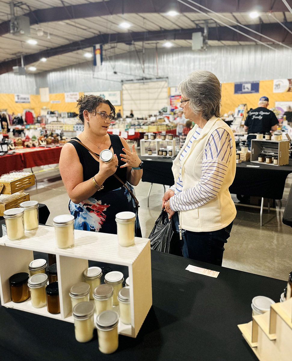 Amanda speaking with a woman customer in her booth at the craft show